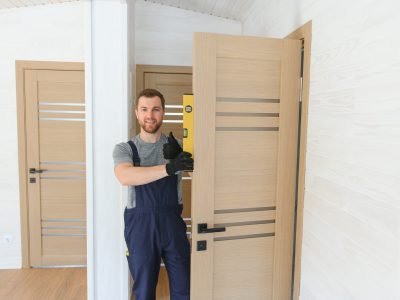 A handsome male worker is installing a new door in a house