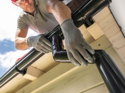 Worker Installing Gutter System on Roof